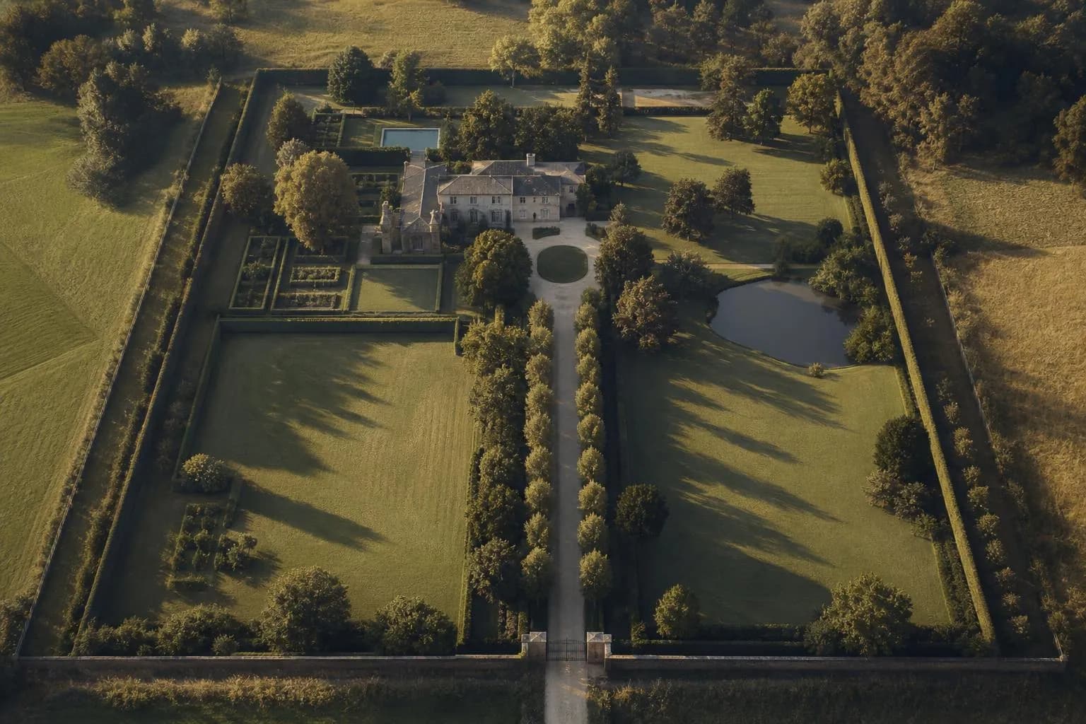 Aerial view of gated estate with defined boundaries, trees, and private drive