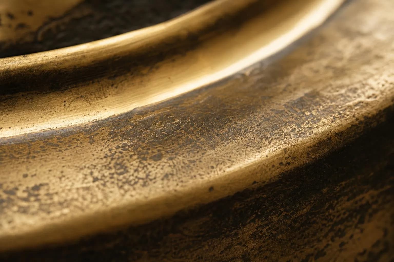 Close-up of textured brass surface with warm light and subtle patina, suggesting depth and enduring value