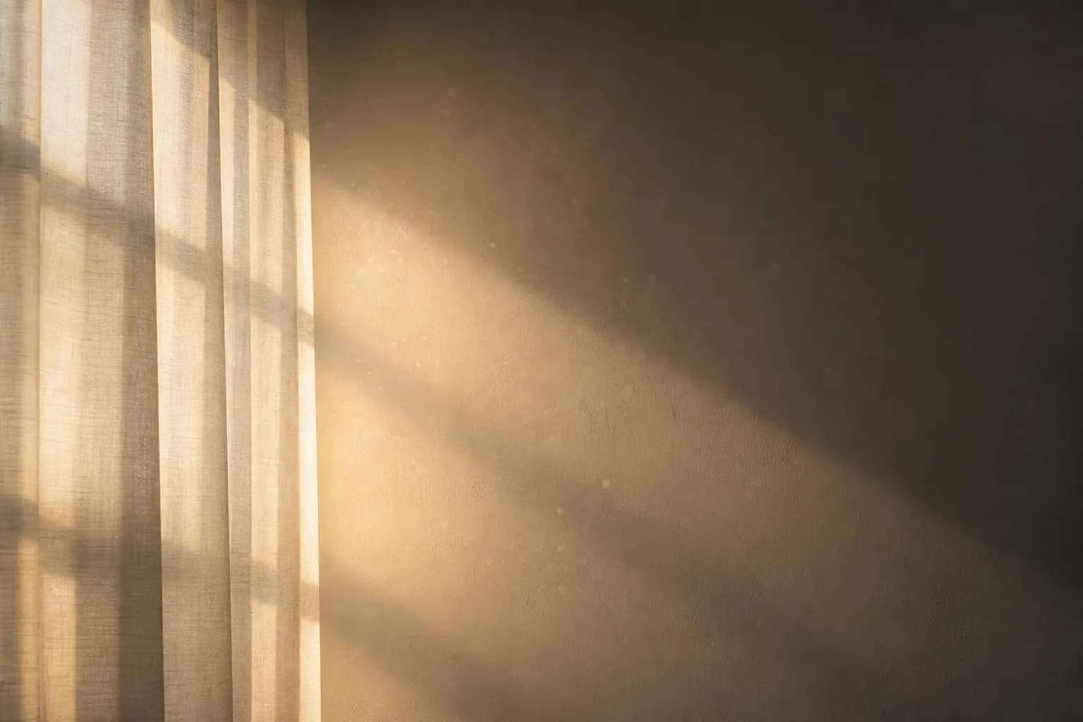 Soft diffused sunlight filtering through translucent curtains onto a plain wall, creating abstract light and shadow