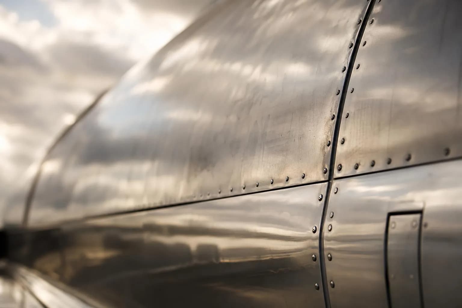 Close-up of polished aircraft fuselage with panel seams and rivets in soft light