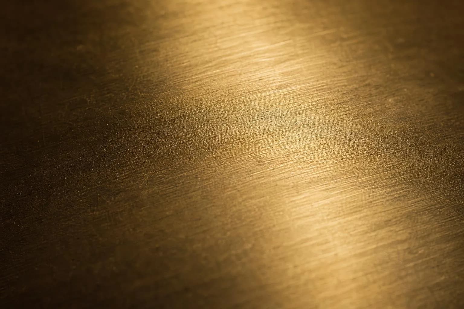Close-up of brushed brass surface with warm raking light revealing fine texture and patina
