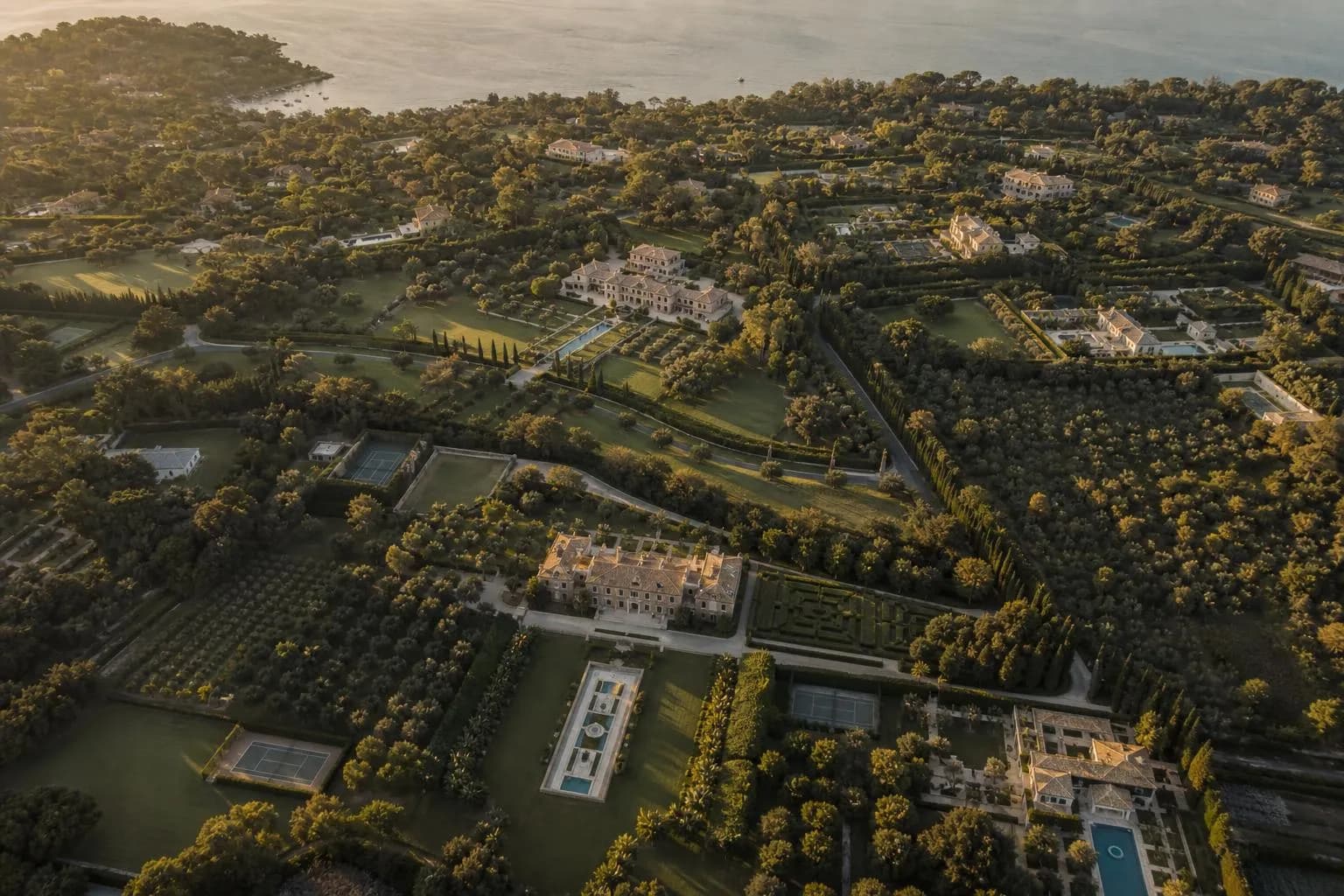 Aerial view of private estates and properties arranged in an intricate, organized pattern across a landscape at golden hour.