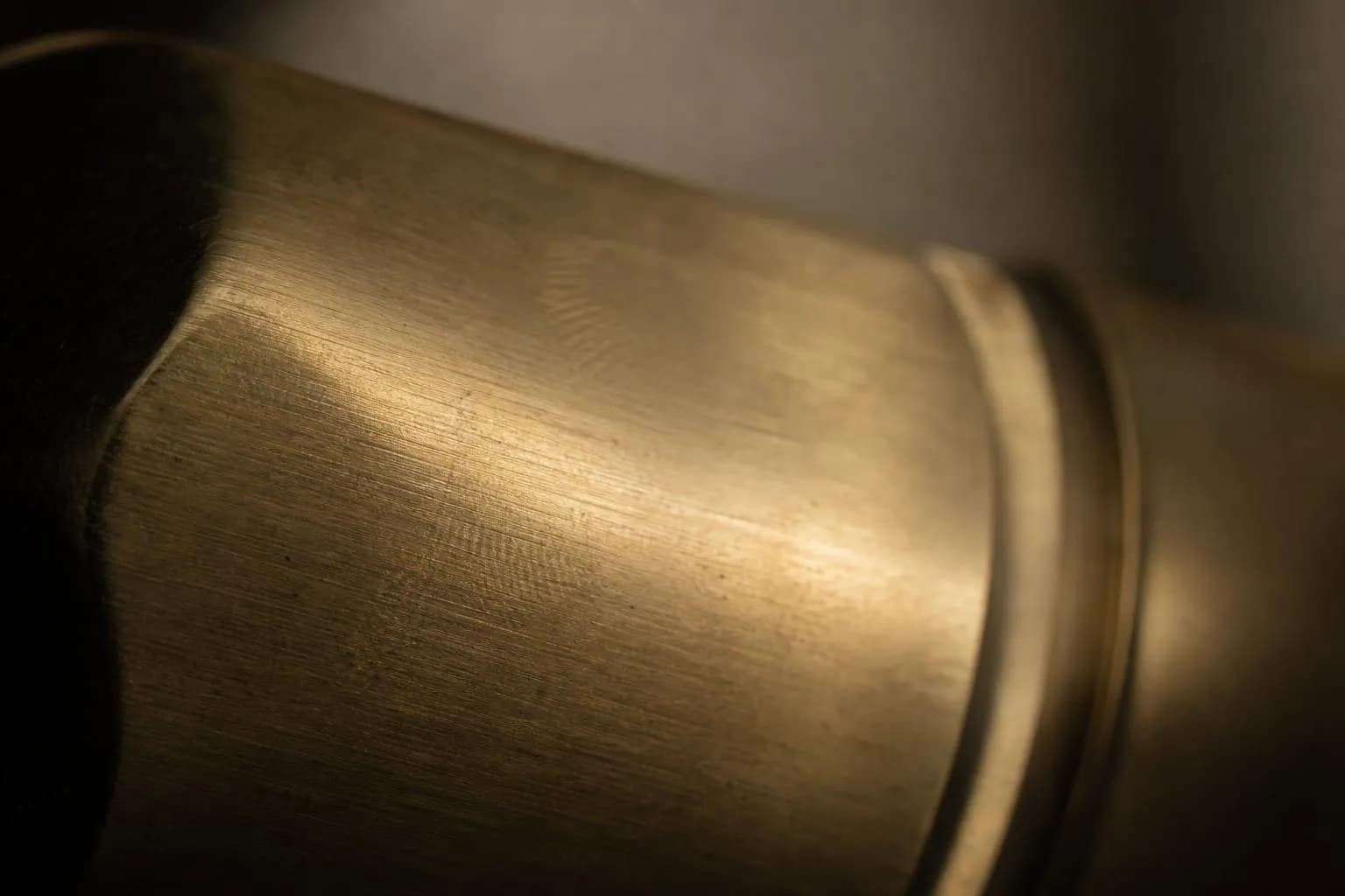 Extreme close-up of brushed brass surface with warm directional light and fine texture detail.