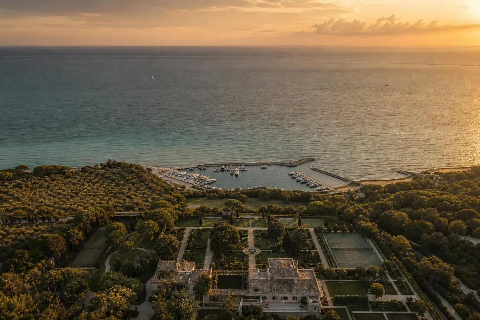 Aerial view of private coastal estate and marina at golden hour, showing geometric precision of demarcated spaces.