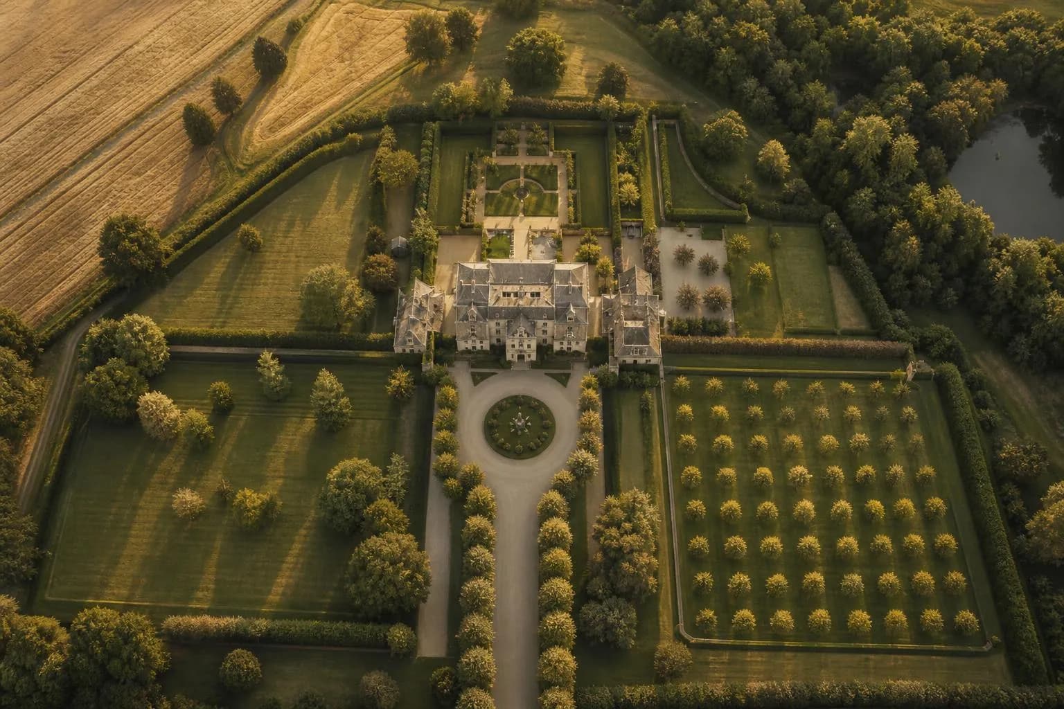 Aerial view of a formal private estate with manicured gardens and structured grounds at sunset.