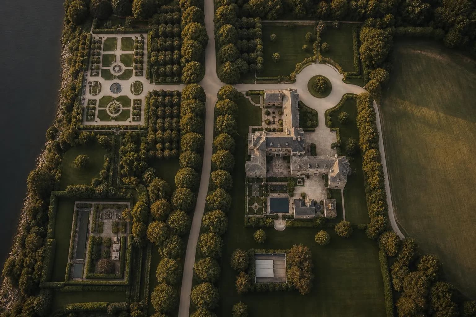 Aerial view of a manicured private estate at dusk, showing distinct zones of land use and careful planning.