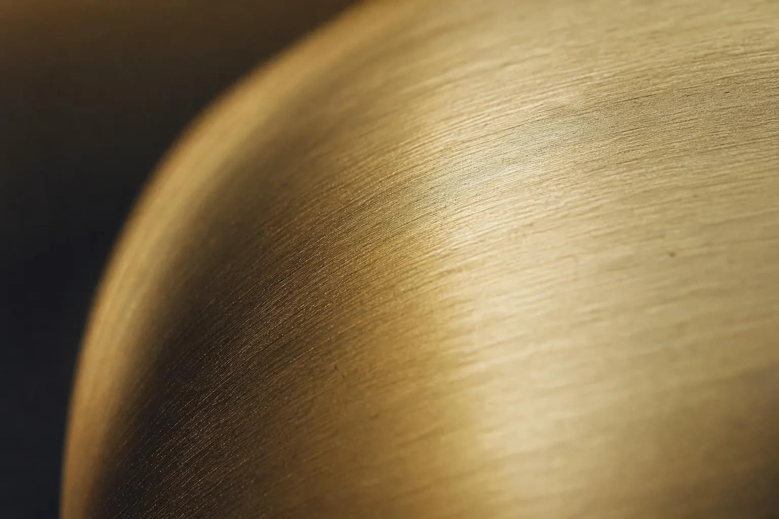 Close-up of brushed brass surface with warm directional light and subtle texture detail