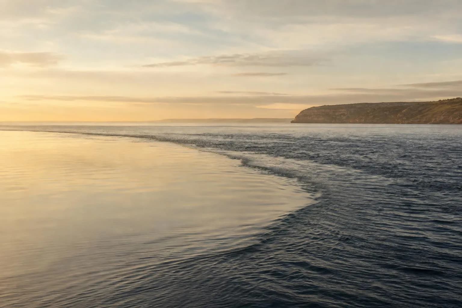 Serene coastal waters at dawn where two currents meet, depicting contrast between permanence and change.