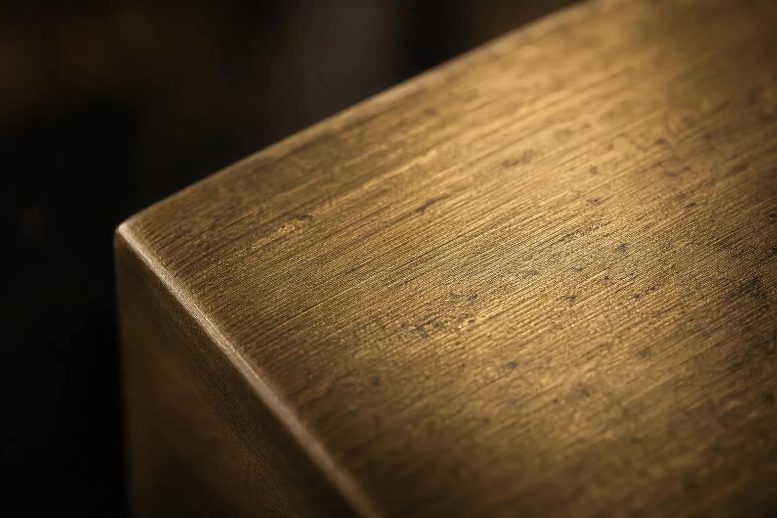 Close-up of brushed brass surface with warm directional light and fine linear texture
