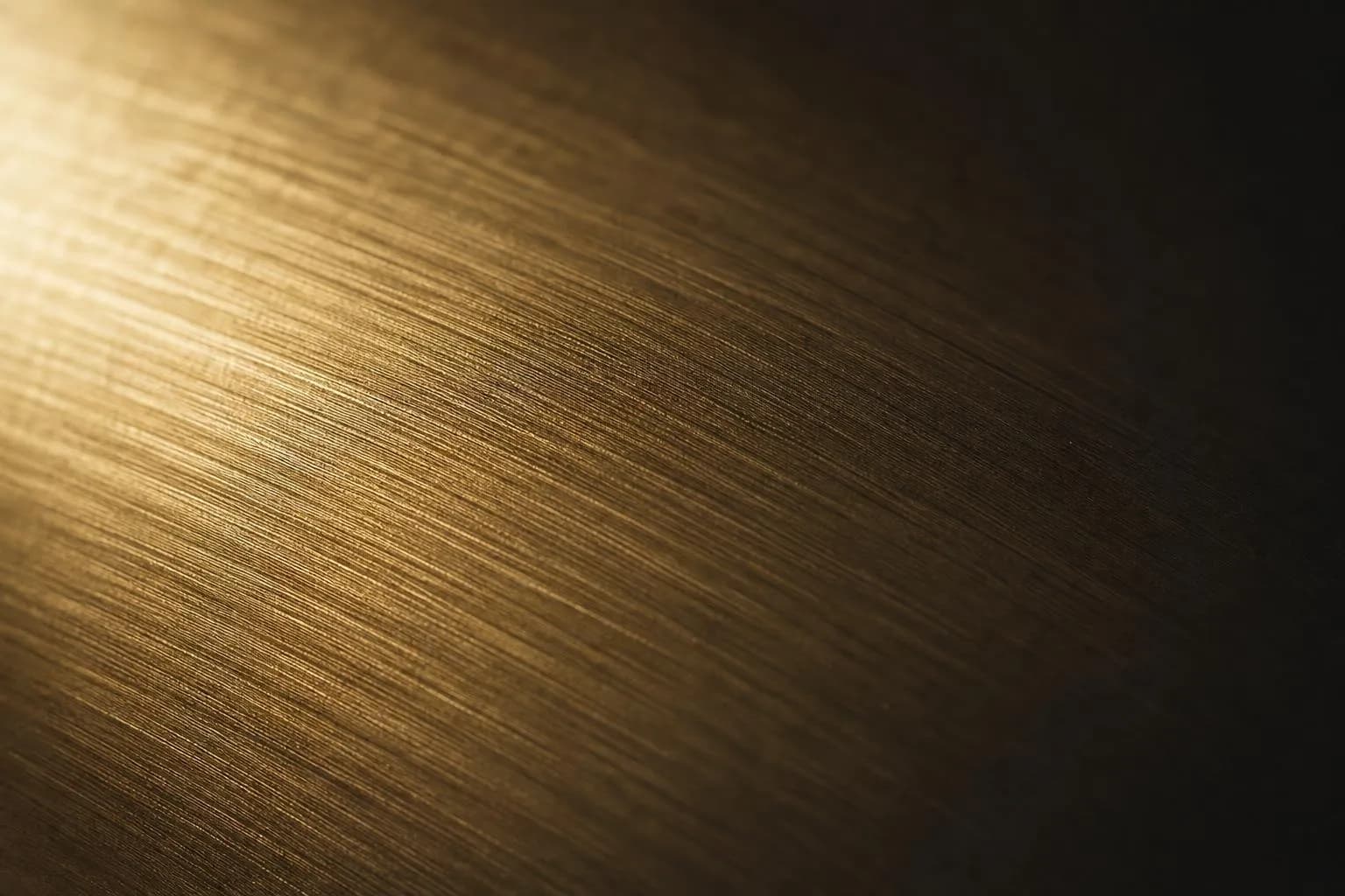 Close-up of brushed brass surface with raked lighting emphasizing fine texture and grain
