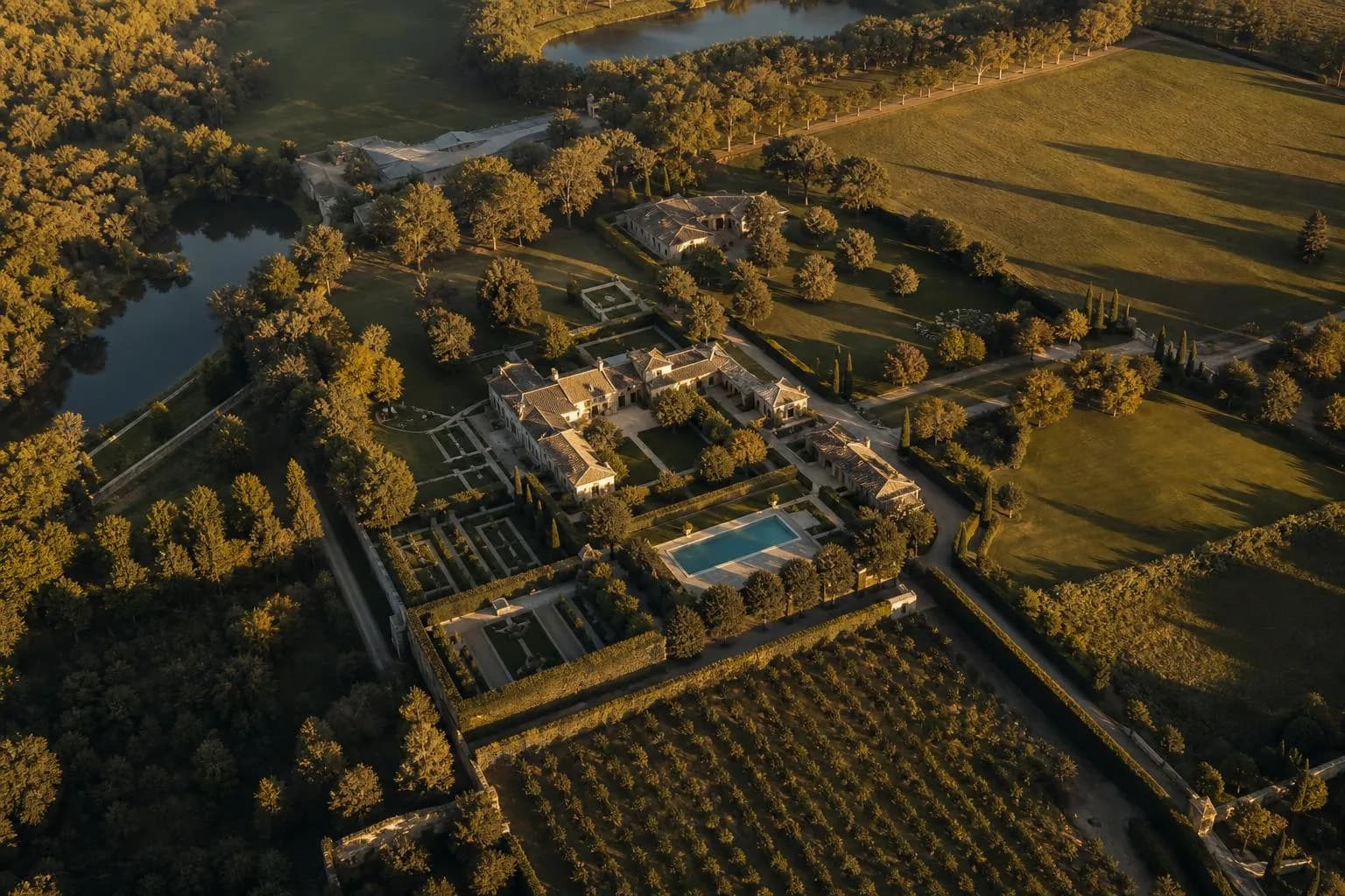 Overhead view of a private estate with manicured grounds and tree-lined paths at sunset