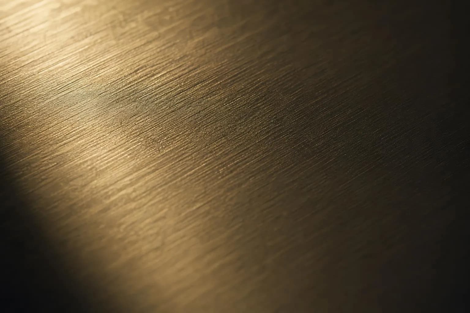 Extreme close-up of brushed brass surface with fine grain texture and raking light
