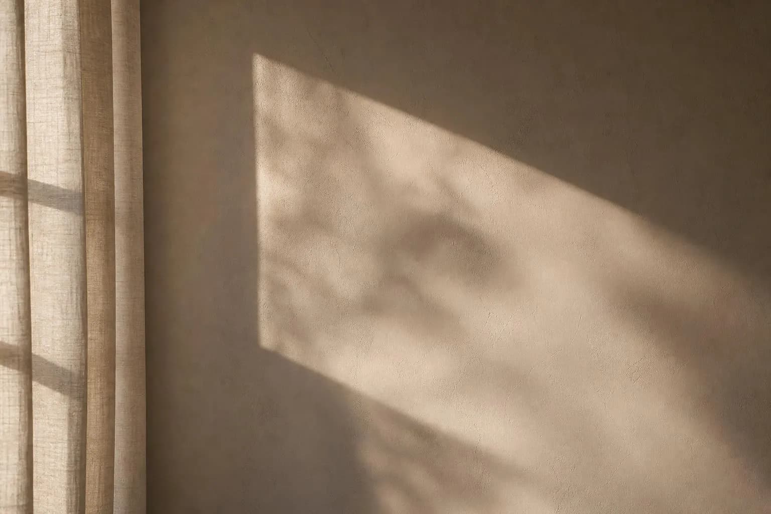 Soft sunlight casting geometric shadows through sheer curtains on a plain wall