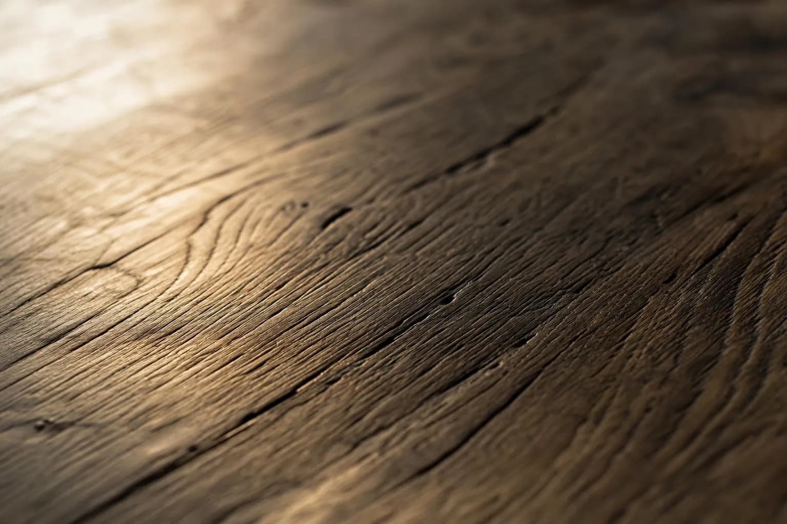 Extreme close-up of aged oak flooring with deep grain texture illuminated by warm light.