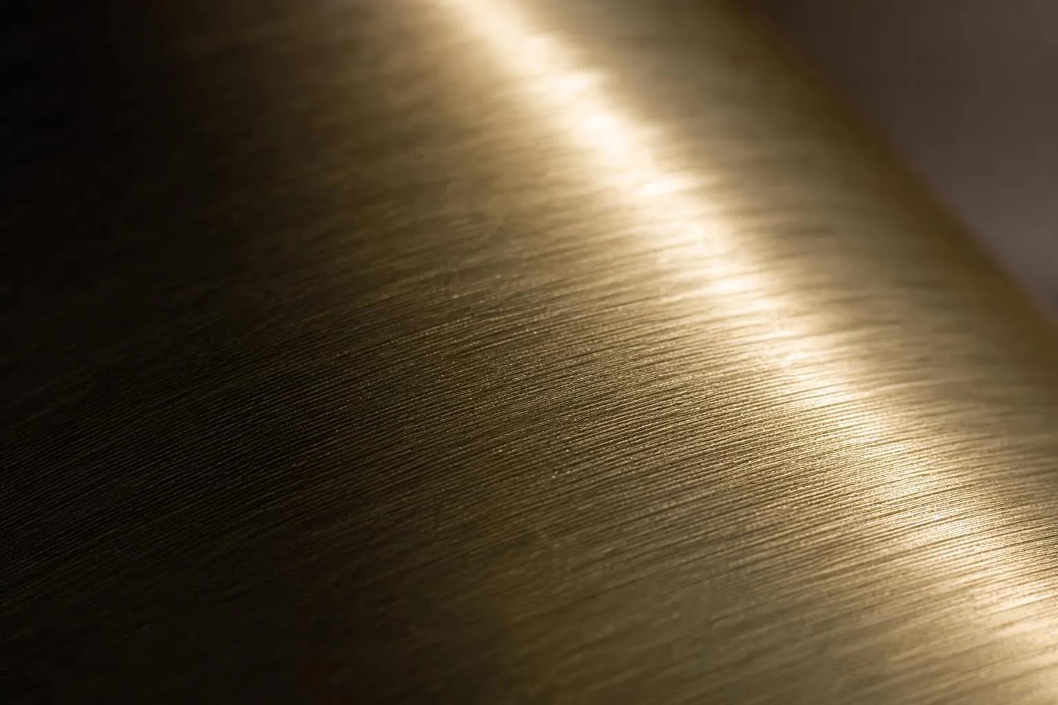 Close-up of brushed brass with directional grain catching light unevenly across the surface