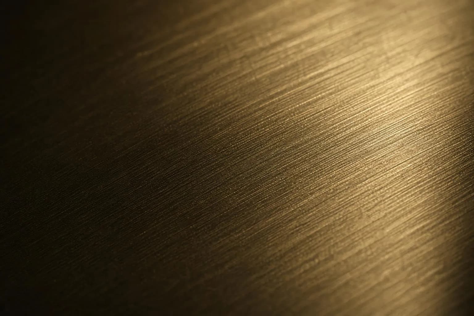 Close-up of brushed brass surface with directional grain pattern and warm sidelight.