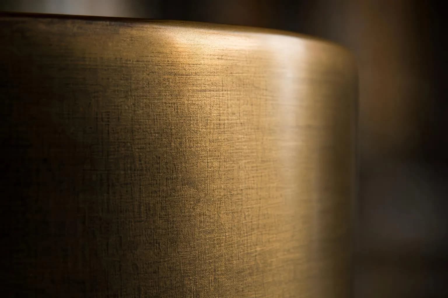 Close-up of brushed brass surface with subtle directional texture and warm light