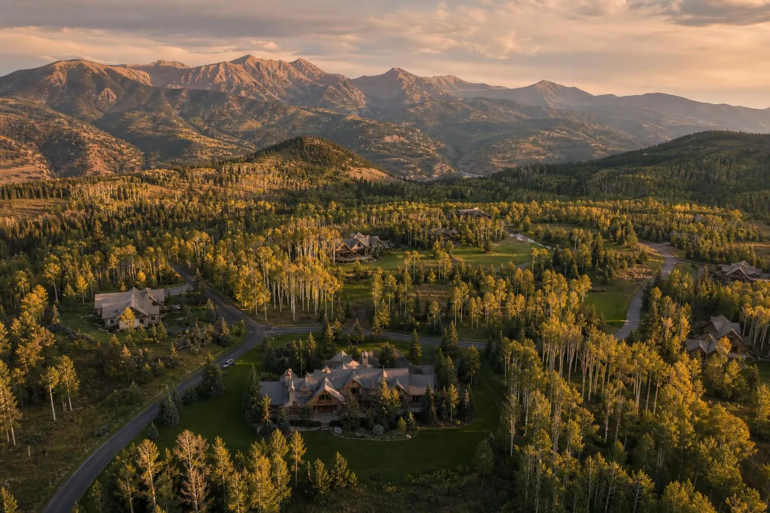 Aerial view of Colorado mountain valley properties at golden hour with aspen forests and private roads.