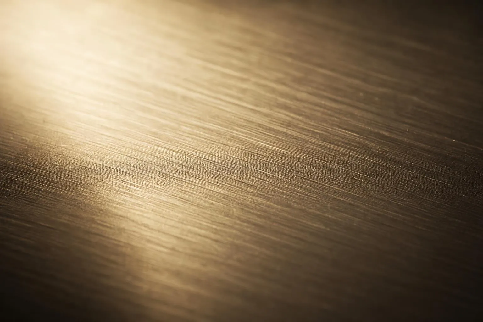 Close-up of brushed metal surface with fine grain texture and warm reflective light