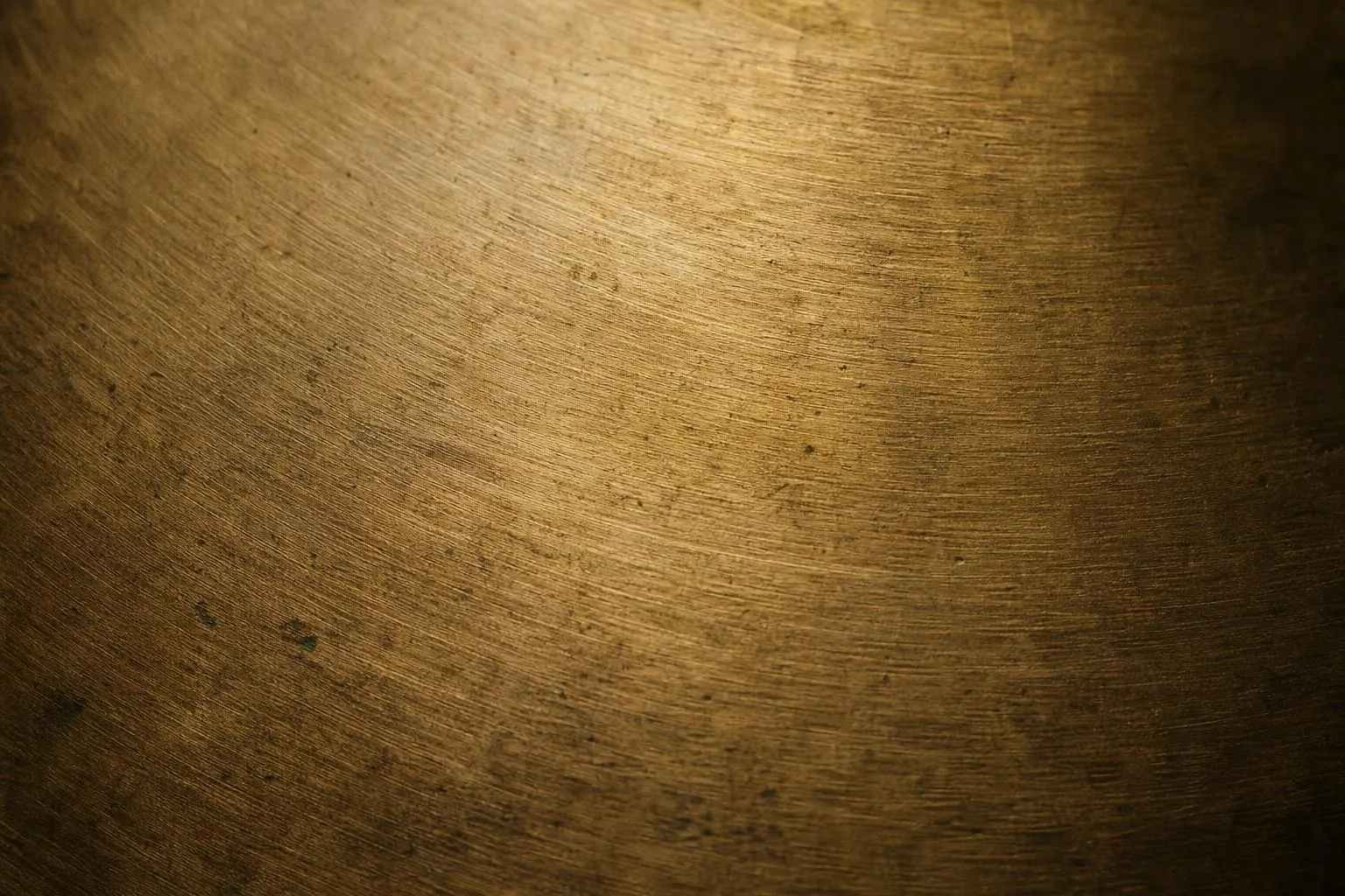 Close-up of brushed brass surface with warm directional lighting and fine texture detail